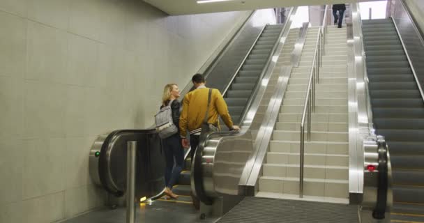 一对身穿休闲装 离开地铁站 站在自动扶梯上笑着和说话的白人夫妇的背影 — 图库视频影像