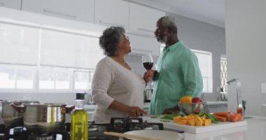 Kıdemli bir Afrikalı Amerikalı çift, Coronavirus covid 19 salgını sırasında karantinada birlikte vakit geçiriyorlar. Ellerinde kırmızı şarap kadehleri ve ağır çekimde içiyorlar.