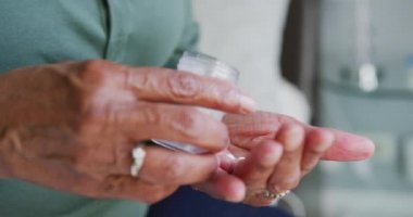 Üst düzey bir Afrikalı Amerikalı kadının Coronavirus covid 19 salgını sırasında karantinaya alınması ve kişisel izolasyon süresince evdeki vaktini evde geçirerek geçirdiği tabletleri yavaş çekimde eline dökerek kapatması.
