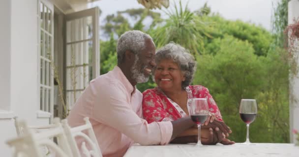 一对资深的非洲裔美国夫妇一起在自家的花园里度过了一段时光 在科罗纳韦病毒肆虐期间 他们在隔离中保持距离和自我隔离 一边微笑着 一边望着别处 桌上拿着酒杯 慢吞吞地走着 — 图库视频影像