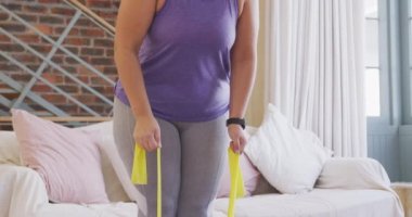 Beyaz kadın vlogger evde zaman geçiriyor, esneme bandı kullanıyor. Karantina karantinasında sosyal uzaklık ve kişisel izolasyon.