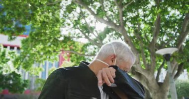 Orta yaşlı beyaz bir adam gün boyunca şehir sokaklarında dolaşır, Coronavirus 'a karşı bir maske takar, covid 19, hapşırırken ağzını kapatır, ağır çekimde..