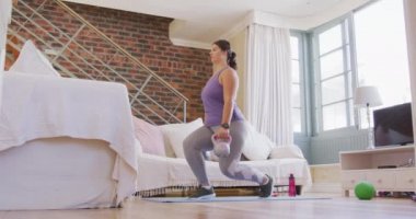Beyaz kadın vlogger evde vakit geçiriyor, yoga minderinde egzersiz yapıyor, dambıl kullanıyor. Karantina karantinasında sosyal uzaklık ve kişisel izolasyon.