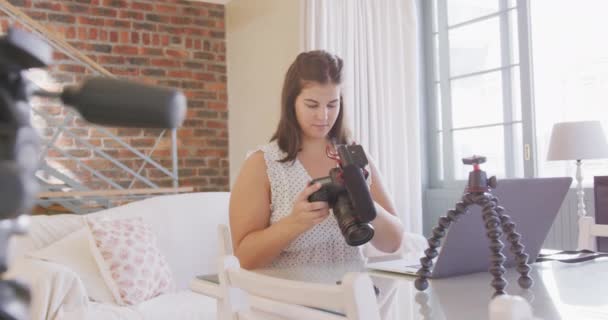 白人女性のVloggerは家で時間を過ごし テーブルに座り ラップトップとカメラを使用して 彼女のVlog用のビデオを準備します 隔離された封鎖における社会的距離と自己隔離 — ストック動画
