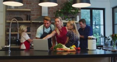 Çok nesilli Kafkas ailesi evde vakit geçiriyorlar, mutfakta duruyorlar, yemek hazırlıyorlar, karantinada dizüstü bilgisayar kullanıyorlar, sosyal uzaklık ve kendilerini izole ediyorlar. Coronavirus covid19 salgını sırasında, ağır çekimde.