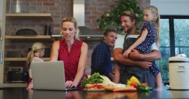 Çok nesilli Kafkas ailesi evde vakit geçiriyorlar, mutfakta duruyorlar, yemek hazırlıyorlar, karantinada dizüstü bilgisayar kullanıyorlar, sosyal uzaklık ve kendilerini izole ediyorlar. Coronavirus covid19 salgını sırasında, ağır çekimde.