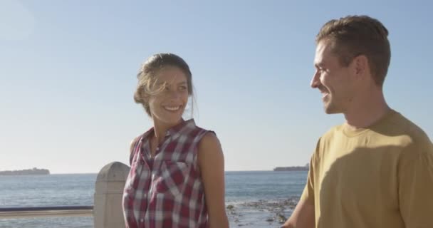 Vista Lateral Jovem Casal Caucasiano Feliz Relaxando Junto Mar Sorrindo — Vídeo de Stock