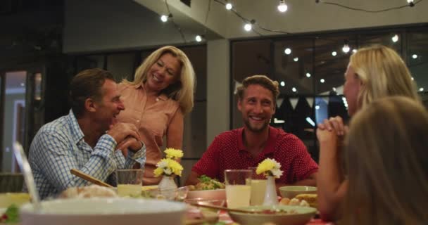 自宅で自分の時間を楽しんで世代の白人の家族 テーブルのそばに座って 一緒に夕食を食べます 話して コロナウイルスの流行中に隔離されたロックダウンでの社会的距離と自己分離19流行 スローモーションで — ストック動画