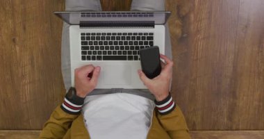Kafkasyalı bir adamın evde vakit geçirmesini, sosyal mesafeyi ve kendini karantina altında tutmasını oturma odasında bir katta oturmasını akıllı telefon ve dizüstü bilgisayar kullanarak izlemesini.