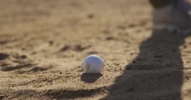 Güneşli bir günde golf sahasında golf kulübünün yakınında, kum sığınağında golf topunu sallarken ve vururken, yavaş çekimde.