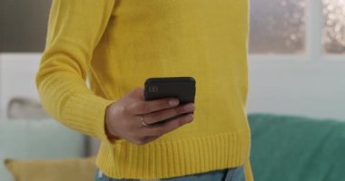 Kafkasyalı bir kadının evinde vakit geçirdiği orta bölüm, sosyal mesafeler ve karantina tecridi, oturma odasında durması, akıllı telefon kullanması.