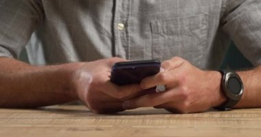 Kafkasyalı bir adamın evdeki vaktini, sosyal mesafeyi ve kendini karantinaya alıp bir masada akıllı telefon kullanarak geçirdiği orta bölüm.