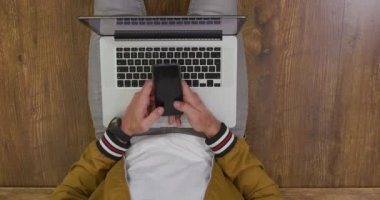 Kafkasyalı bir adamın evde vakit geçirmesini, sosyal mesafeyi ve kendini karantina altında tutmasını oturma odasında bir katta oturmasını, akıllı telefon kullanmasını, dizüstü bilgisayarı ile dizüstü bilgisayar kullanmasını.