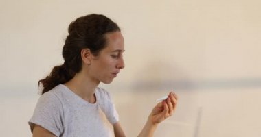 Beyaz kadın, Coronavirus covid 19 salgını sırasında karantinada kendini izole ederek ve sosyal mesafeyi koruyarak evde vakit geçiriyor. Ateşini ölçüyor ve öksürüyor.