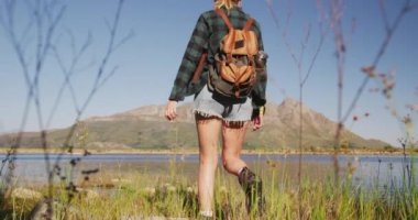 Kafkasyalı bir kadının dağlara yaptığı gezide, güneşli bir günde, yavaş çekimde kıyıda durarak iyi vakit geçirmesi.