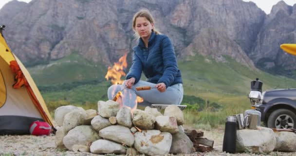 白种人女人在登山路上玩得很开心 坐在篝火边 用木棍做香肠 动作缓慢 — 图库视频影像