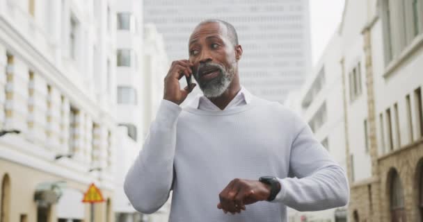 昼間アフリカ系アメリカ人の男性が街中に立ってスマートフォンを使っていました — ストック動画