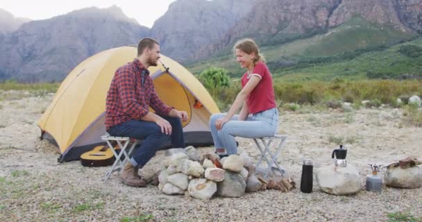 白种人夫妇在山上度过了一段愉快的时光 他们坐在帐篷前篝火边 慢吞吞地谈着笑着 — 图库视频影像
