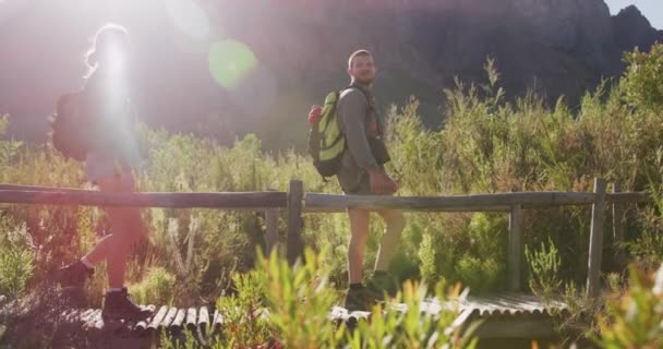 山への旅行で楽しい時間を過ごしている白人夫婦 橋の上を歩いて 景色を楽しみます 晴れた日に スローモーションで — ストック動画