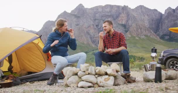 白种人夫妇在登山途中玩得很开心 他们坐在篝火边 慢吞吞地吃香肠 — 图库视频影像