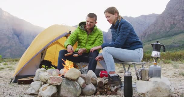 白种人夫妇在登山旅行中度过了一段愉快的时光 他们坐在篝火边 用木棍做香肠 动作缓慢 — 图库视频影像