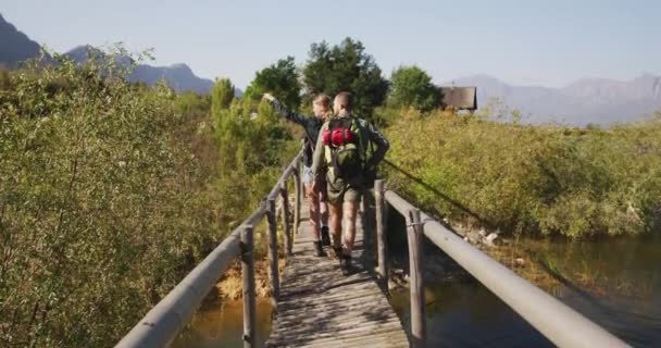 白种人夫妇在登山旅行中度过了一段愉快的时光 在桥上散步 在阳光灿烂的日子里欣赏风景 动作缓慢 — 图库视频影像
