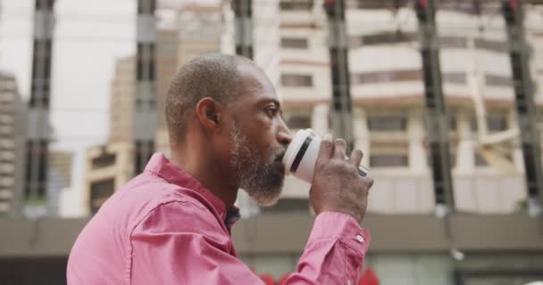 非裔美国人在城市街道上走来走去 走在大街上 喝着外卖咖啡 接着智能手机 — 图库视频影像