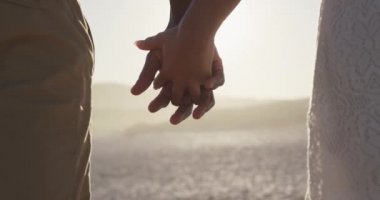 Afrika kökenli Amerikalı bir çiftin tropikal bir plajda güneşlenip el ele tutuşurken yavaş çekimde lens alevleriyle aydınlanan bir bölümü.