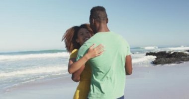 Afrika kökenli Amerikalı bir çiftin tropikal bir plajda güneşlenirken birbirlerine bakıp gülümsemelerini ve dans etmelerini ağır çekimde seyretmek.
