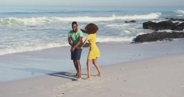 Afrika kökenli Amerikalı bir çiftin tropik bir plajda eğlenirken gülümsemesi ve sırtında ağır çekimde taşıdığı görüntüler.