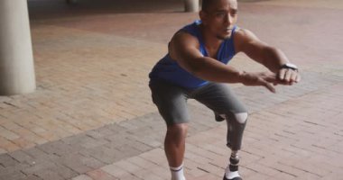 Engelli, protez bacaklı, kentsel alanda çalışan, ağır çekimde çömelmiş, engelli bir ırkın yan görüntüsü.