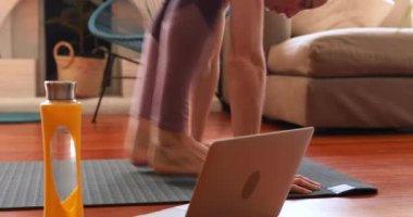 Beyaz kadın spor giyer, Coronavirus sırasında evde vakit geçirir, kovid19 kilitlenir, oturma odasında yoga minderi üzerinde egzersiz yapar, sosyal mesafeli davranır ve kendini izole eder..