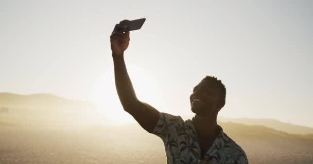 一个非裔美国人在热带海滩上享受阳光下的时光 带着自拍和微笑 背带着淡淡的照明弹 慢吞吞地向前看 — 图库视频影像