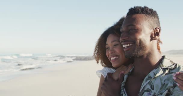 熱帯のビーチで太陽の下で時間を楽しんでいるアフリカ系アメリカ人のカップルの近くにサイドビュー 笑顔と離れて見て スローモーションで — ストック動画