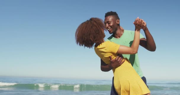 アフリカ系アメリカ人のカップルの側のビュー熱帯のビーチで太陽の下で時間を楽しんで お互いを見て 笑顔と踊り スローモーションで — ストック動画