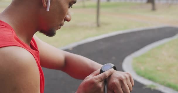 Vista Lateral Hombre Raza Mixta Haciendo Ejercicio Parque Comprobando Tiempo — Vídeo de stock