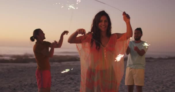 日落时分 一群多种族的朋友在热带海滩共度佳节 他们面带微笑 与火花玩耍 动作缓慢 — 图库视频影像