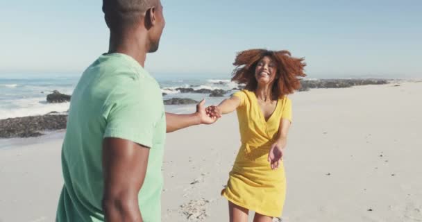 熱帯のビーチで太陽の下で時間を楽しんでいるアフリカ系アメリカ人のカップルのフロントビュー お互いを見て 手を取り合って 笑顔と歩く スローモーションで — ストック動画