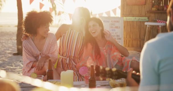 在日落时分 一群混血的种族朋友在热带海滩共度佳节 坐在桌旁 慢吞吞地笑了起来 — 图库视频影像