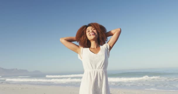 熱帯のビーチで太陽の下で時間を楽しんでいるアフリカ系アメリカ人女性の前で手を上げて回転しながら — ストック動画
