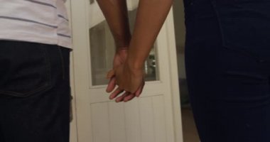 Melez bir çiftin arka görüntüsü. Bahçede birlikte vakit geçiriyorlar. Güneşli bir günde, yavaş çekimde evlerine yürüyüp el ele tutuşuyorlar.