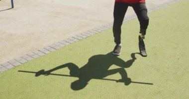 Ön manzara, protez bacaklı, engelli bir ırkın düşük kesimi, gezinti güvertesinde çalışıyor, omuzlarında çan çubuğuyla çömelme hareketleri yapıyor, kulaklıkla müzik dinliyor, yavaş çekimde.