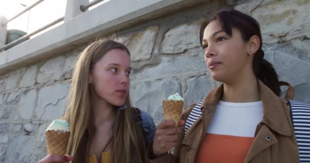白人と混じった人種の少女の側の景色晴れた日に一緒に遊び アイスクリームを食べ 壁のそばに立って スローモーションで — ストック動画