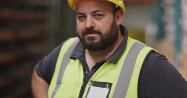 Bir fabrikada çalışan beyaz bir erkek fabrika işçisinin portresi. Hidrolik ekipman üretiyor. Yelek ve sert bir şapka giyiyor..