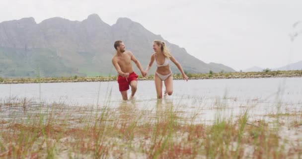 白种人夫妇在登山途中玩得很开心 穿着游泳衣 慢吞吞地在湖中跑来跑去 — 图库视频影像