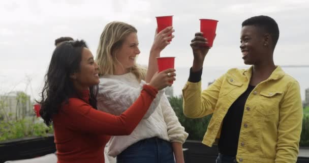 アジア系 白人系 混合人種の女性が赤いカップから飲み物を飲んでいますが 彼らの友人はゆっくりとした動きで話しています — ストック動画