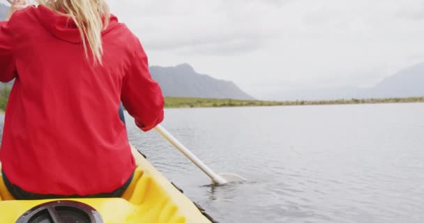 山への旅行で楽しい時間を過ごしている白人女性 湖でカヤック パドルを保持 スローモーションで — ストック動画