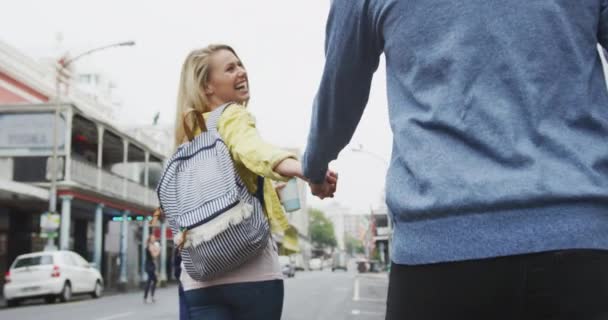 幸せな白人カップルアウトし 日中街の通りで にこにこと手を取り合いながら街を探索 — ストック動画