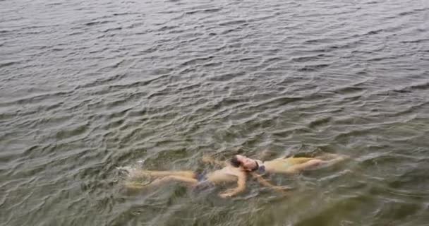 这对白种人夫妇穿着游泳衣 在湖中慢悠悠地漂浮着 在登山途中玩得很开心 — 图库视频影像