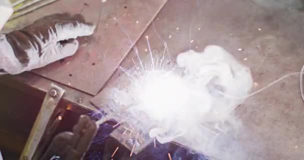 在一家液压设备制造厂工作的白人男性工人手的特写 他们身穿深色围裙 戴着焊面和手套 站在工作台上 慢动作地焊接 — 图库视频影像